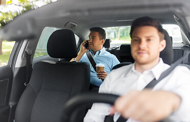 Image showing male passenger with coffee calling on phone in car