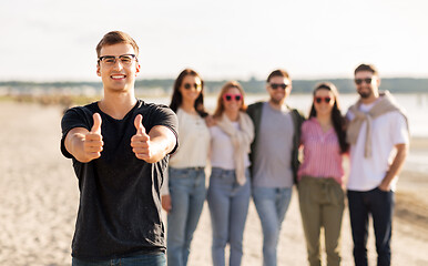 Image showing happy man with friends on beach showing thumbs up