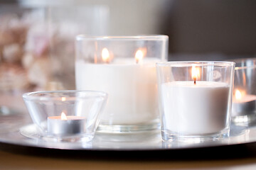 Image showing burning white fragrance candles on tray on table