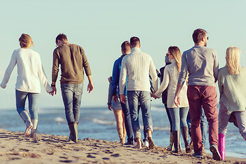 Image showing Group of friends running on beach during autumn day