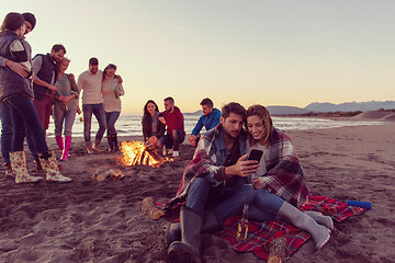 Image showing Couple enjoying bonfire with friends on beach