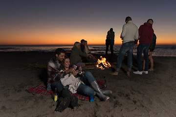 Image showing Couple enjoying bonfire with friends on beach