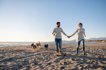 Image showing couple with dog having fun on beach on autmun day