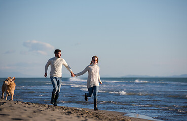 Image showing couple with dog having fun on beach on autmun day