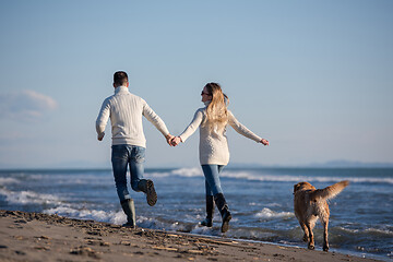 Image showing couple with dog having fun on beach on autmun day