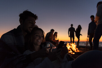 Image showing Couple enjoying bonfire with friends on beach