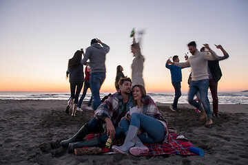 Image showing Couple enjoying with friends at sunset on the beach