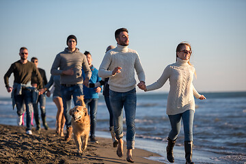 Image showing Group of friends running on beach during autumn day