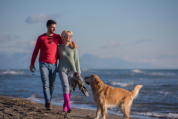 Image showing couple with dog having fun on beach on autmun day