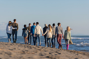 Image showing Group of friends running on beach during autumn day