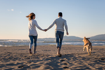 Image showing couple with dog having fun on beach on autmun day