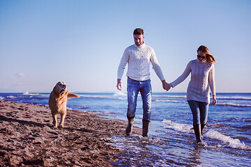 Image showing couple with dog having fun on beach on autmun day