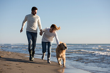 Image showing couple with dog having fun on beach on autmun day