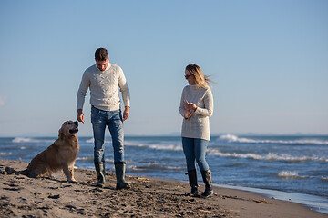 Image showing couple with dog having fun on beach on autmun day