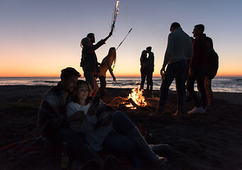 Image showing Couple enjoying bonfire with friends on beach