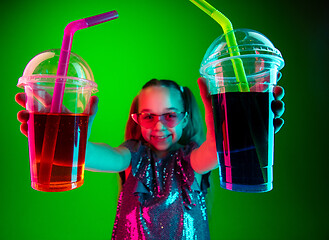 Image showing The happy teen girl standing and smiling against green lights background.