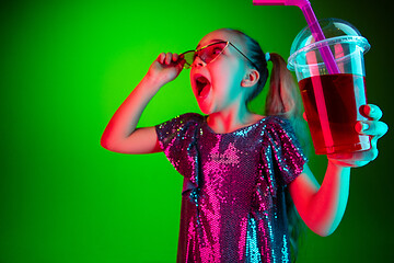 Image showing The happy teen girl standing and smiling against green lights background.