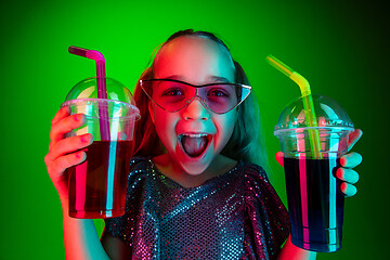 Image showing The happy teen girl standing and smiling against green lights background.