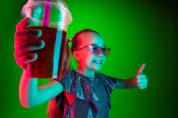 Image showing The happy teen girl standing and smiling against green lights background.