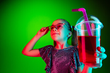 Image showing The happy teen girl standing and smiling against green lights background.