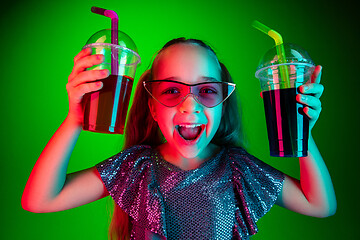 Image showing The happy teen girl standing and smiling against green lights background.