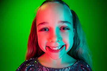 Image showing The happy teen girl standing and smiling against green lights background.