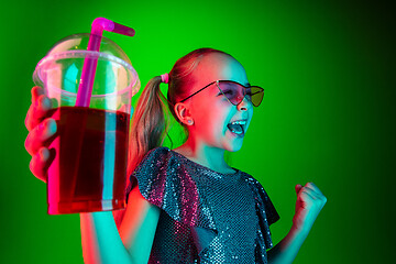 Image showing The happy teen girl standing and smiling against green lights background.