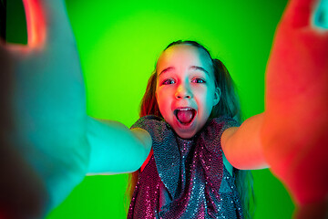 Image showing The happy teen girl standing and smiling against green lights background.