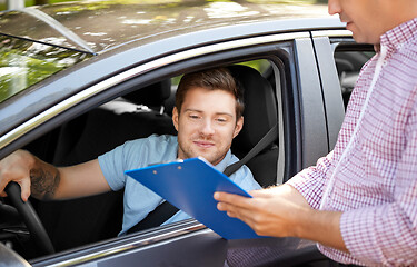 Image showing car driving instructor with clipboard and driver