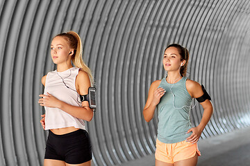 Image showing young women with earphones and smartphones running