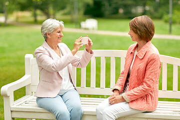 Image showing senior woman photographing her friend at park