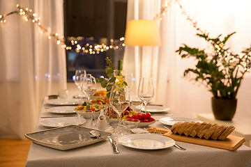 Image showing table served with plates, wine glasses and food