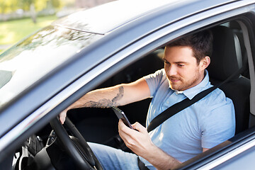 Image showing man driving car and using smartphone