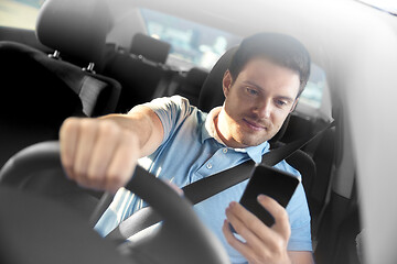 Image showing man driving car and using smartphone