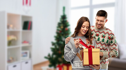 Image showing happy couple in christmas sweaters with gift box