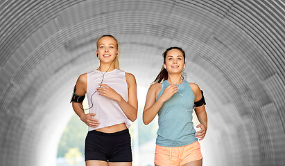 Image showing young women with earphones and smartphones running