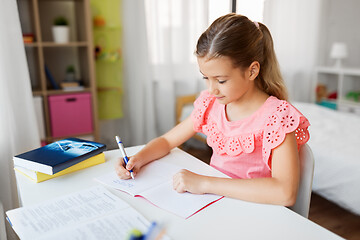 Image showing student girl with book writing to notebook at home