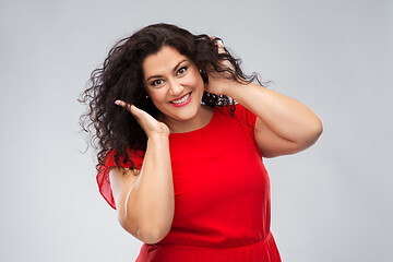 Image showing happy woman touching her hair over grey background