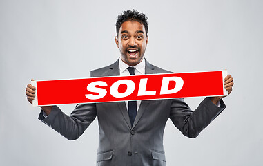 Image showing happy indian male realtor with red sold banner