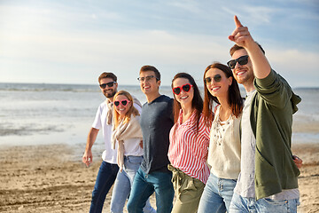 Image showing happy friends walking along summer beach