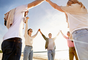 Image showing happy friends holding hands on summer beach