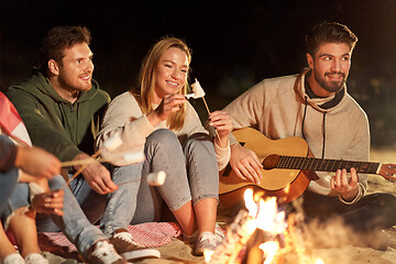 Image showing friends roasting marshmallow and playing guitar