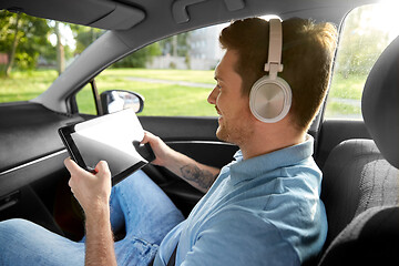 Image showing passenger in headphones with tablet pc in taxi car