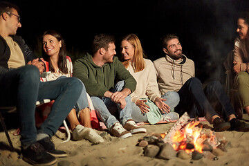 Image showing group of friends sitting at camp fire on beach