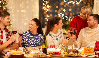 Image showing happy friends drinking red wine at christmas party