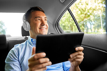 Image showing passenger with headphones using tablet pc in car