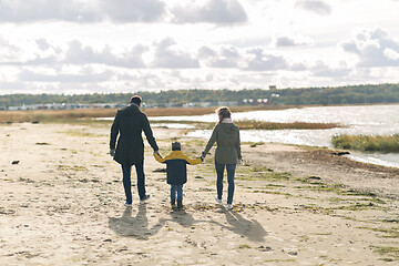 Image showing happy family walking along autumn beach