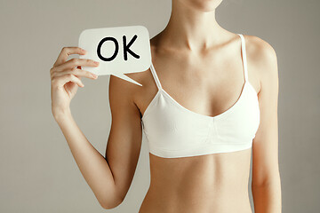 Image showing Young adult woman holding paper card with sign ok.