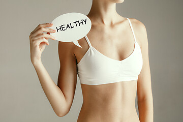 Image showing Young adult woman holding paper card with word HEALTHY.