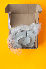 Image showing Upon opening, the parcel contained a broken plate, yellow background